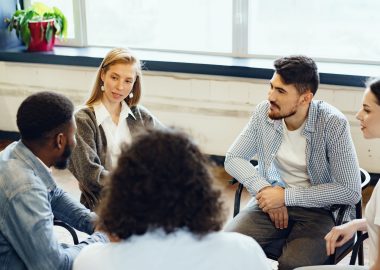Young people sitting in a circle and having a group discussion